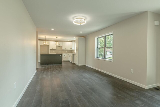 600 8th Ave, New Glarus, WI 53574 - unfurnished living room with baseboards, dark wood-style flooring, recessed lighting, and a chandelier