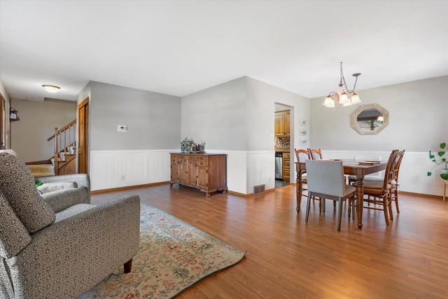 8317 S 42nd St, Franklin, WI 53132 - dining space featuring a chandelier, wainscoting, wood finished floors, and stairs