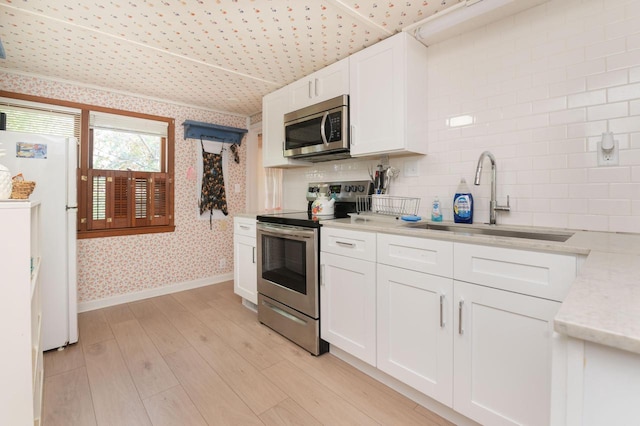 W4943 County Rd S, Horicon, WI 53032 - kitchen with stainless steel appliances, a sink, wallpapered walls, baseboards, and white cabinets