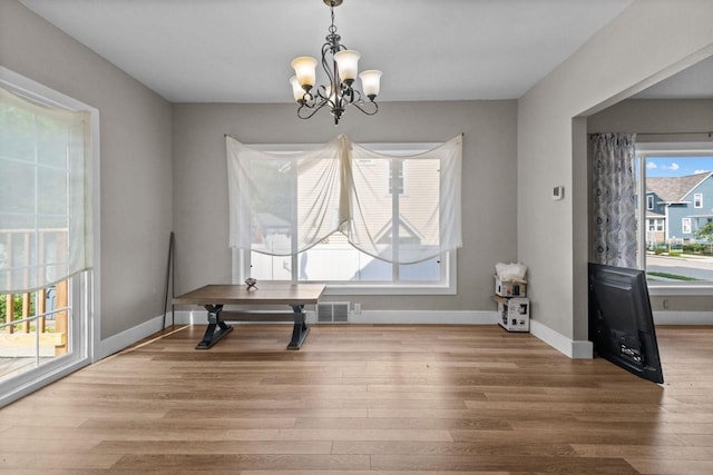 417 E Lincoln Ave, Oshkosh, WI 54901 - unfurnished dining area featuring a chandelier, wood finished floors, and baseboards