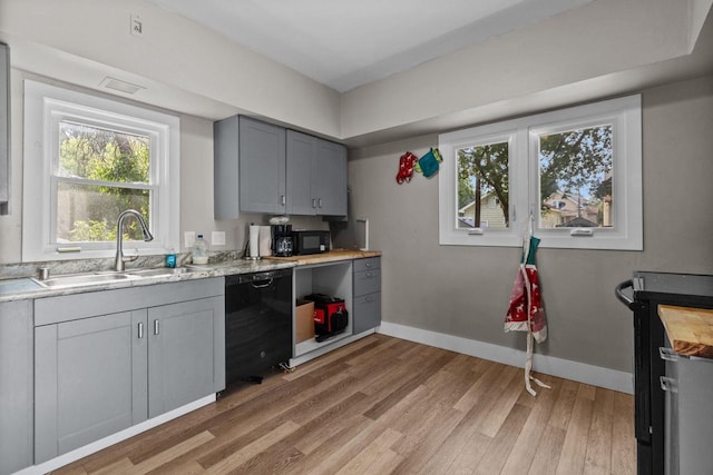 417 E Lincoln Ave, Oshkosh, WI 54901 - kitchen featuring black appliances, light wood finished floors, light countertops, baseboards, and a sink