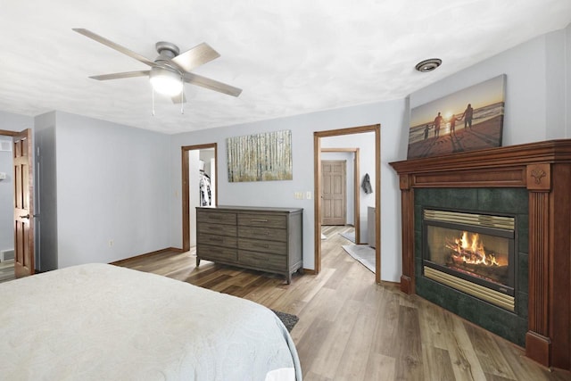 6500 E Decorah Ave, Oshkosh, WI 54902 - bedroom with light wood-style floors, a tiled fireplace, baseboards, and a ceiling fan