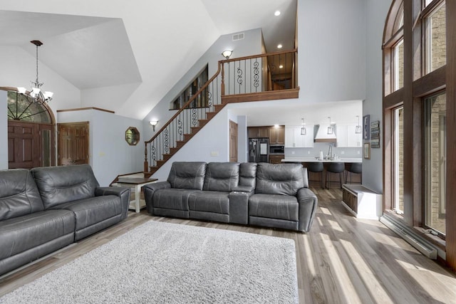6500 E Decorah Ave, Oshkosh, WI 54902 - living room with high vaulted ceiling, stairs, a chandelier, and light wood-type flooring