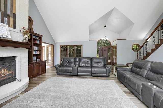 6500 E Decorah Ave, Oshkosh, WI 54902 - living area featuring high vaulted ceiling, a chandelier, a brick fireplace, stairs, and light wood-style flooring