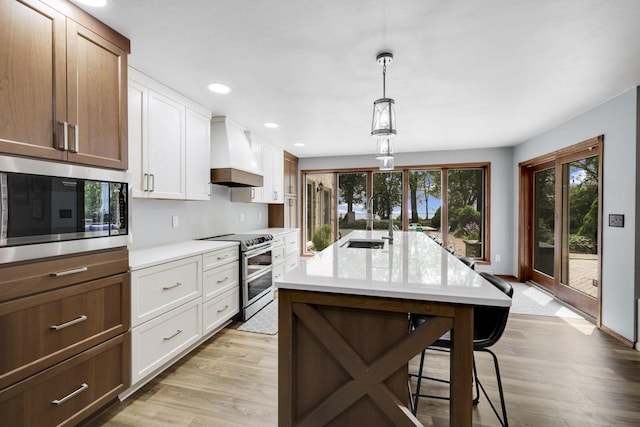 6500 E Decorah Ave, Oshkosh, WI 54902 - kitchen with appliances with stainless steel finishes, custom range hood, a breakfast bar area, light wood-style flooring, and recessed lighting