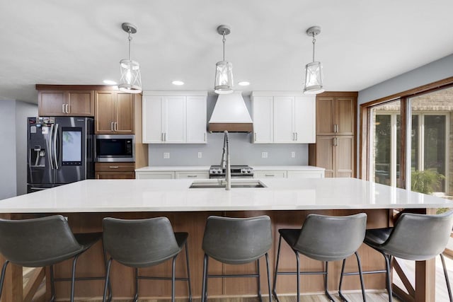 6500 E Decorah Ave, Oshkosh, WI 54902 - kitchen with appliances with stainless steel finishes, custom range hood, a large island with sink, light countertops, and white cabinetry