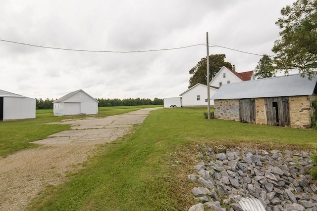 W6497 Vandre Rd, Johnson Creek, WI 53038 - view of green lawn featuring a detached garage, an outbuilding, and driveway