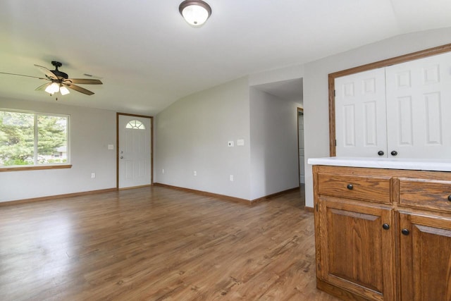 9219 Caddy Ln, Caledonia, WI 53108 - kitchen featuring lofted ceiling, light wood finished floors, baseboards, ceiling fan, and brown cabinetry