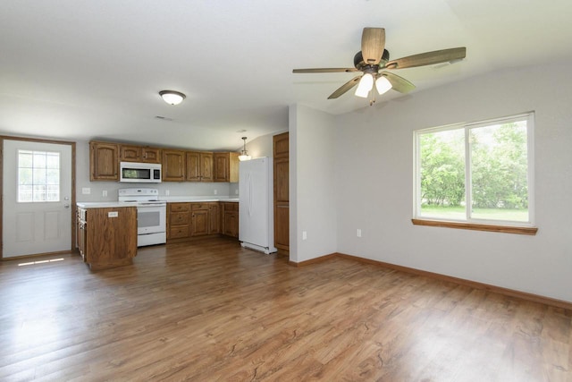 9219 Caddy Ln, Caledonia, WI 53108 - kitchen featuring white appliances, brown cabinetry, light countertops, wood finished floors, and baseboards