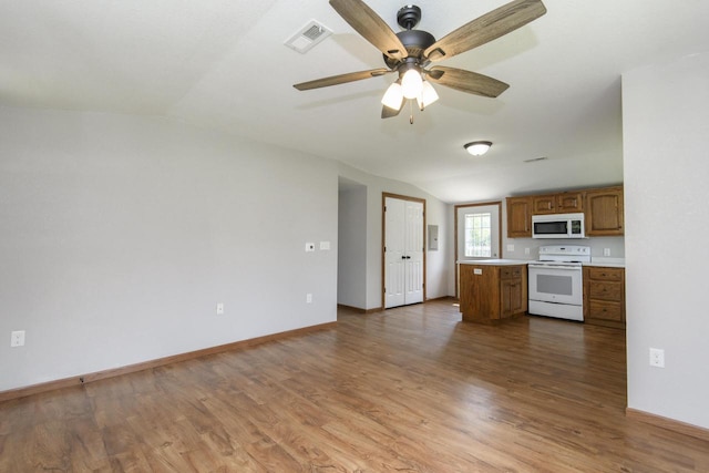 9219 Caddy Ln, Caledonia, WI 53108 - kitchen with white appliances, brown cabinets, vaulted ceiling, wood finished floors, and open floor plan