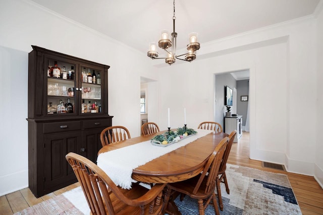 2205 Salisbury Rd, West Bend, WI 53090 - dining space featuring a chandelier, light wood finished floors, ornamental molding, and baseboards