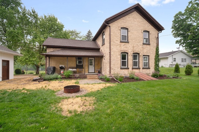 2205 Salisbury Rd, West Bend, WI 53090 - rear view of property featuring a lawn, a fire pit, brick siding, and covered porch