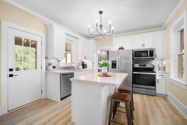 2205 Salisbury Rd, West Bend, WI 53090 - kitchen featuring appliances with stainless steel finishes, light wood-type flooring, a chandelier, a center island, and white cabinetry