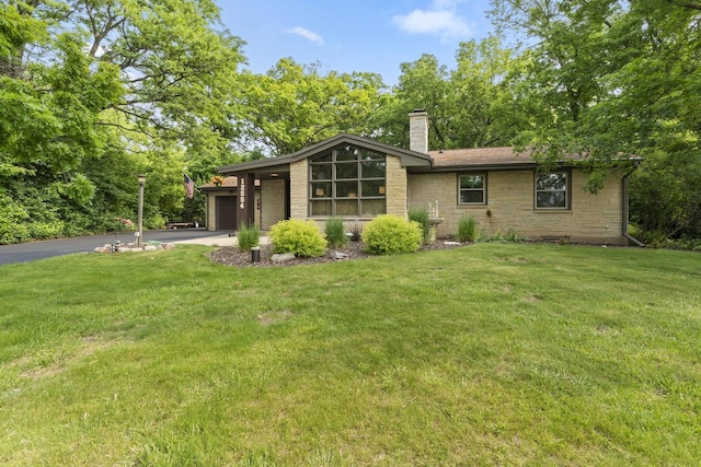 12554 Knoll Rd, Elm Grove, WI 53122 - back of property featuring a chimney, asphalt driveway, a lawn, a garage, and stone siding