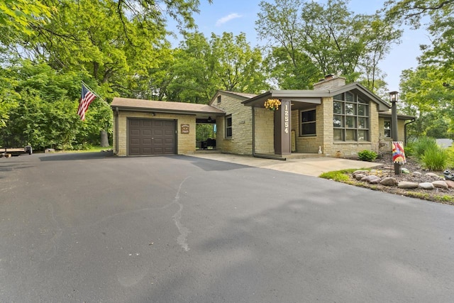 12554 Knoll Rd, Elm Grove, WI 53122 - view of front facade featuring stone siding, a garage, driveway, and a chimney