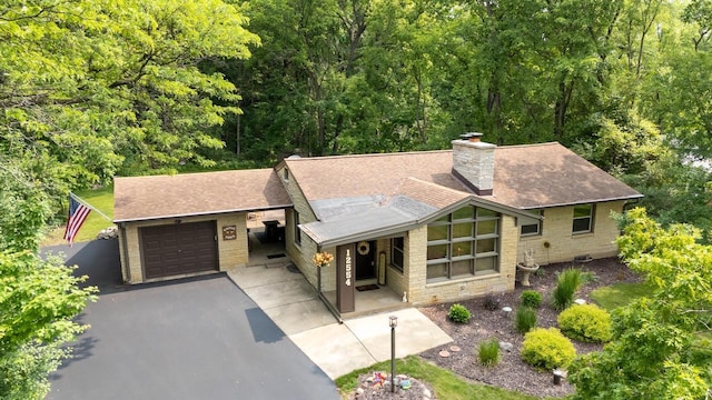 12554 Knoll Rd, Elm Grove, WI 53122 - view of front of house featuring a garage, driveway, roof with shingles, a chimney, and stone siding
