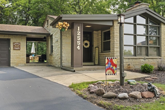 12554 Knoll Rd, Elm Grove, WI 53122 - view of exterior entry featuring stone siding, brick siding, and a chimney