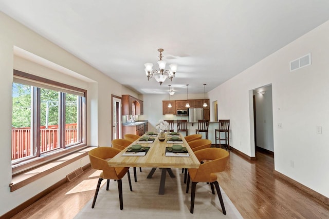100 Accipiter Ct, Burlington, WI 53105 - dining space with wood finished floors, a chandelier, and baseboards