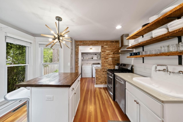 170 N Lakeshore Dr, Fontana, WI 53125 - kitchen with a sink, stainless steel appliances, open shelves, separate washer and dryer, and wall chimney range hood