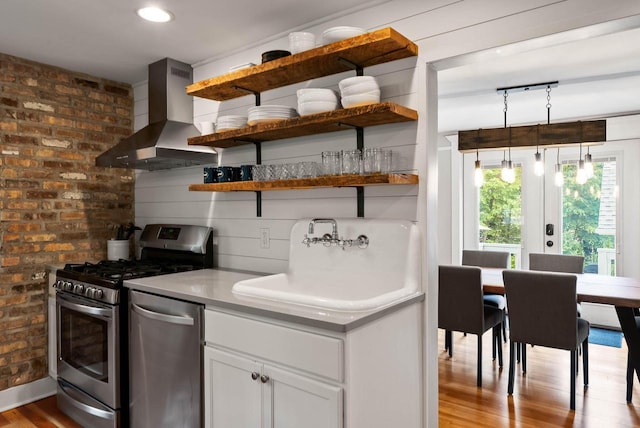 170 N Lakeshore Dr, Fontana, WI 53125 - kitchen featuring wall chimney exhaust hood, appliances with stainless steel finishes, a sink, open shelves, and wood finished floors