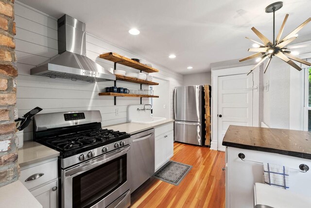 170 N Lakeshore Dr, Fontana, WI 53125 - kitchen featuring stainless steel appliances, wall chimney range hood, light wood finished floors, white cabinets, and recessed lighting