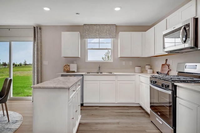 5010 Linden Rd, Mount Pleasant, WI 53403 - kitchen featuring appliances with stainless steel finishes, a sink, light wood-style flooring, white cabinets, and a kitchen island