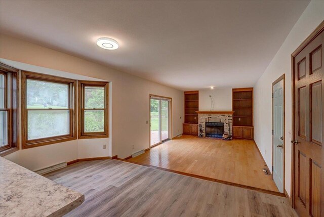1230 N Westfield Rd, Madison, WI 53717 - unfurnished living room featuring light wood-style floors, a brick fireplace, a baseboard heating unit, and built in features