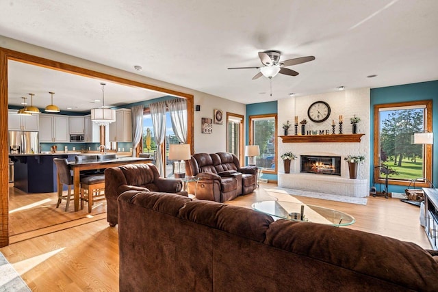 W4745 Briar Dr, Elkhorn, WI 53121 - living area featuring a ceiling fan, healthy amount of natural light, a brick fireplace, and light wood-type flooring