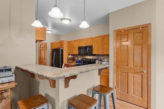 691 N River St Unit 1, Merrimac, WI 53561 - kitchen featuring black appliances, a breakfast bar, tasteful backsplash, light wood-type flooring, and a peninsula