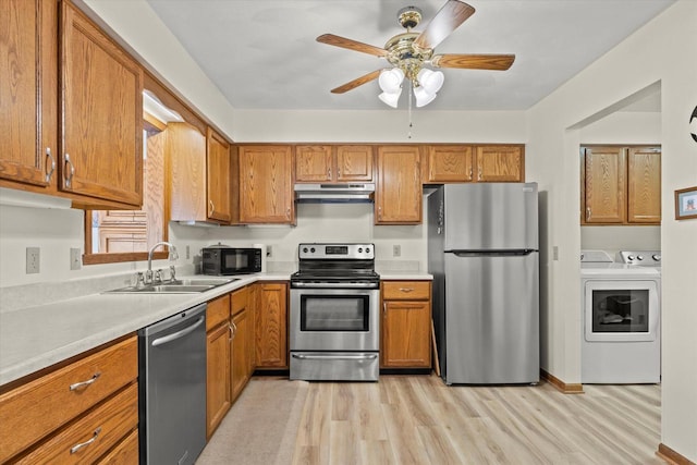 636 Westbury Ln Unit 12, Delavan, WI 53115 - kitchen with appliances with stainless steel finishes, under cabinet range hood, washing machine and clothes dryer, a sink, and light wood-style flooring