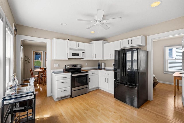 1568 S 63rd St, West Allis, WI 53214 - kitchen featuring white microwave, electric stove, freestanding refrigerator, white cabinetry, and recessed lighting