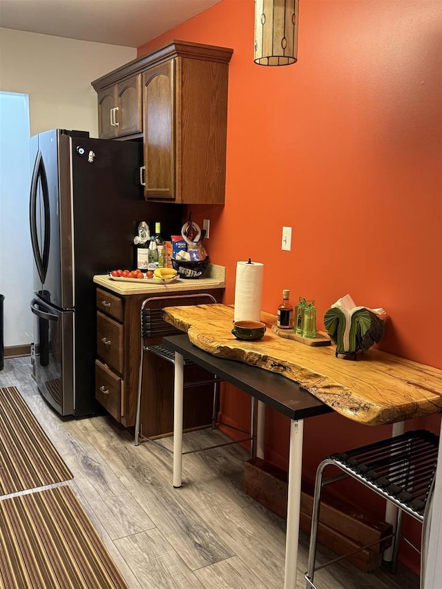 2470 W Good Hope Rd Unit 168, Glendale, WI 53209 - kitchen with light wood-style floors, freestanding refrigerator, a kitchen bar, light countertops, and dark brown cabinets