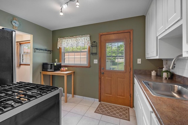 2943 S 102nd St, West Allis, WI 53227 - kitchen with appliances with stainless steel finishes, a sink, white cabinets, light tile patterned floors, and dark countertops