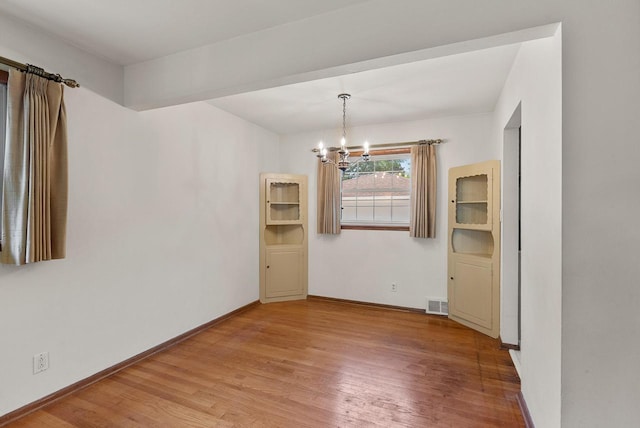 2943 S 102nd St, West Allis, WI 53227 - unfurnished dining area with a chandelier, light wood-style flooring, and baseboards