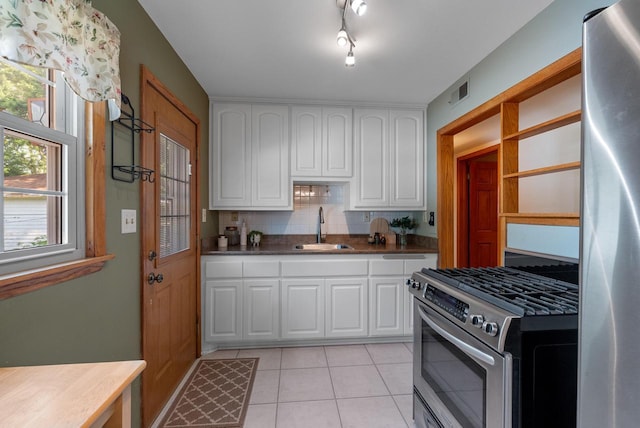 2943 S 102nd St, West Allis, WI 53227 - kitchen featuring appliances with stainless steel finishes, a sink, white cabinets, light tile patterned floors, and tasteful backsplash