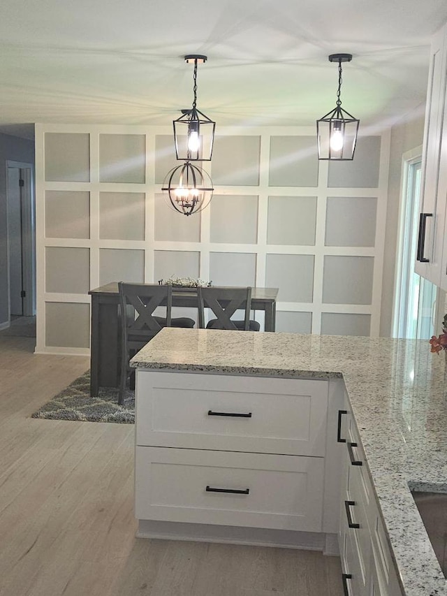 233 Inlet Shores Dr, Delavan, WI 53115 - kitchen featuring white cabinetry, light wood-type flooring, light stone counters, pendant lighting, and a chandelier