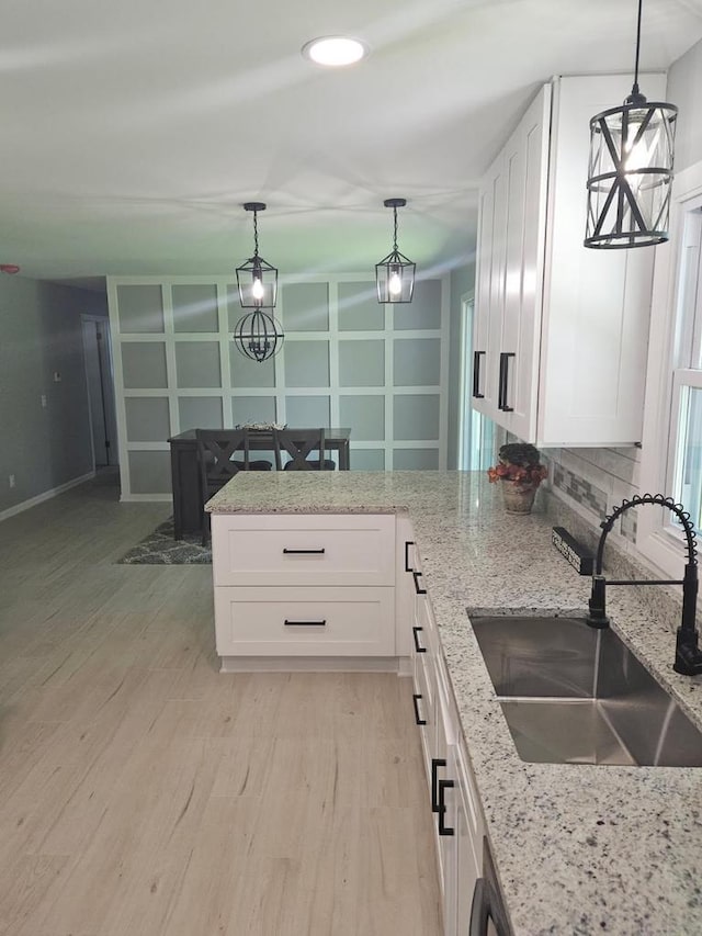 233 Inlet Shores Dr, Delavan, WI 53115 - kitchen featuring a sink, white cabinets, light stone counters, and hanging light fixtures