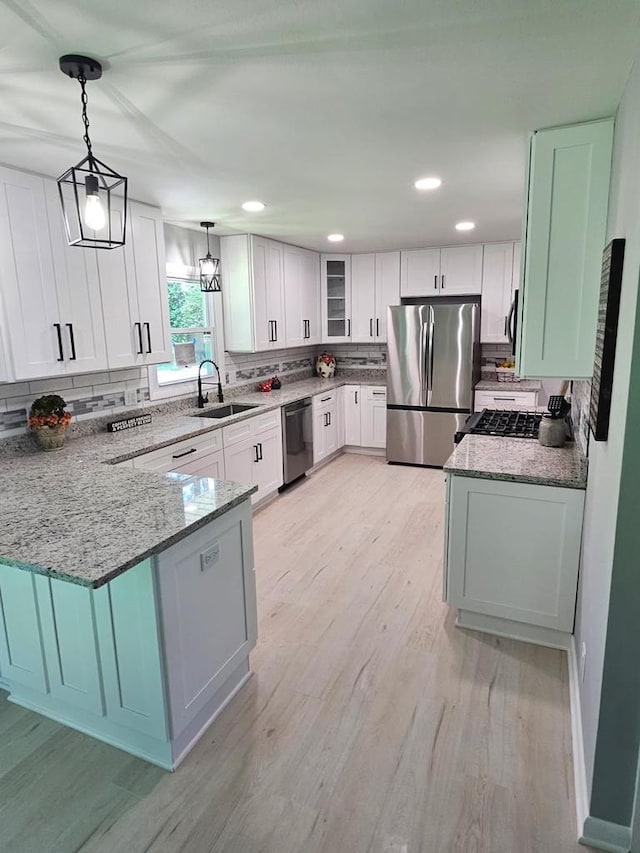 233 Inlet Shores Dr, Delavan, WI 53115 - kitchen featuring stainless steel appliances, a sink, light stone counters, a peninsula, and recessed lighting