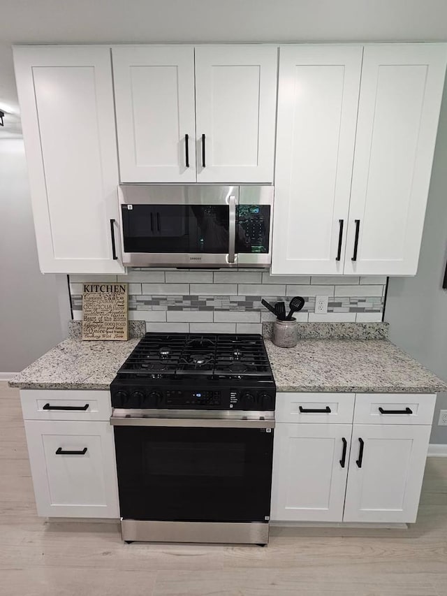 233 Inlet Shores Dr, Delavan, WI 53115 - kitchen with stainless steel microwave, black gas range oven, tasteful backsplash, and light stone counters