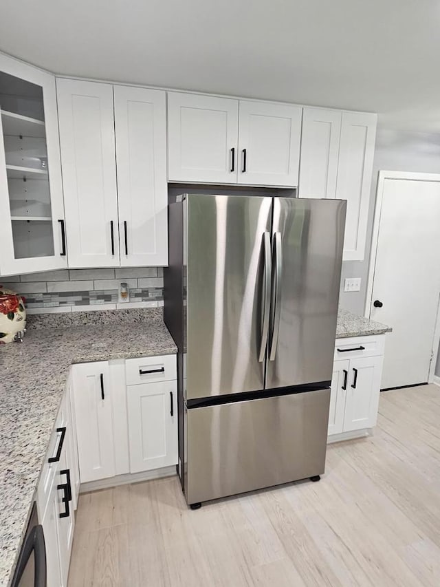 233 Inlet Shores Dr, Delavan, WI 53115 - kitchen featuring freestanding refrigerator, light wood-style floors, white cabinetry, light stone counters, and tasteful backsplash