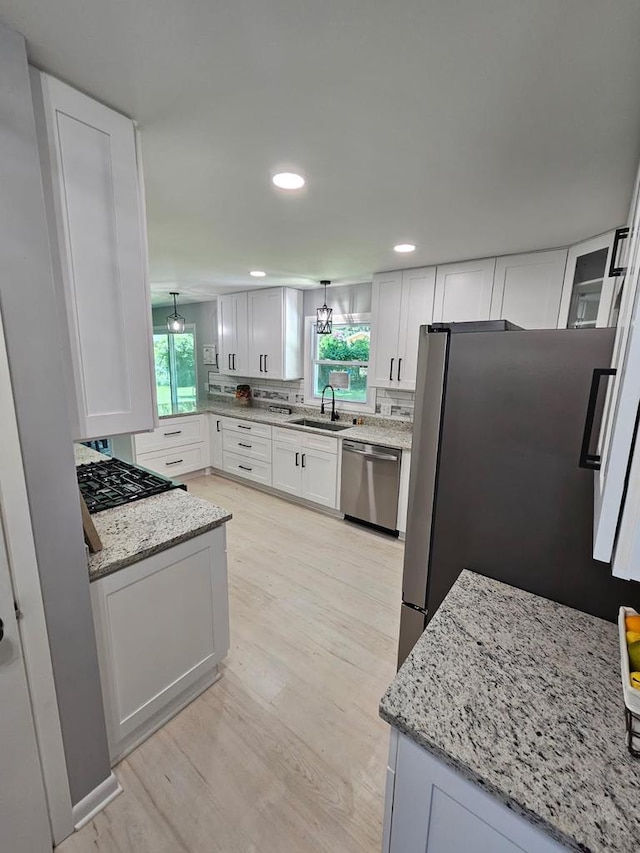 233 Inlet Shores Dr, Delavan, WI 53115 - kitchen featuring stainless steel appliances, light wood finished floors, light stone countertops, white cabinetry, and plenty of natural light