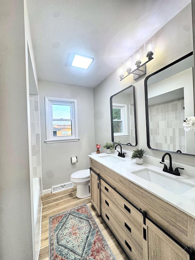 722 Michigan Ave, North Fond Du Lac, WI 54937 - full bath with double vanity, wood finished floors, toilet, a bathtub, and baseboards