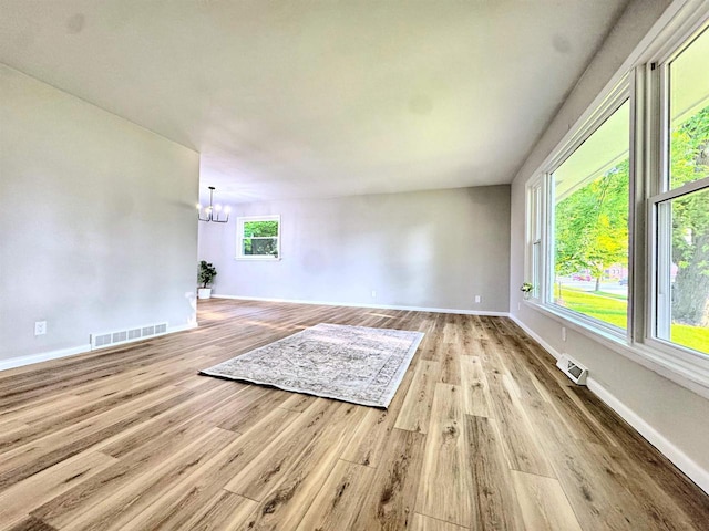 722 Michigan Ave, North Fond Du Lac, WI 54937 - unfurnished living room featuring a chandelier, baseboards, and wood finished floors