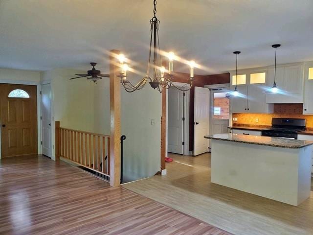 9350 County Road F, Milladore, WI 54454 - kitchen with black range, under cabinet range hood, light wood-style floors, white cabinets, and stone counters