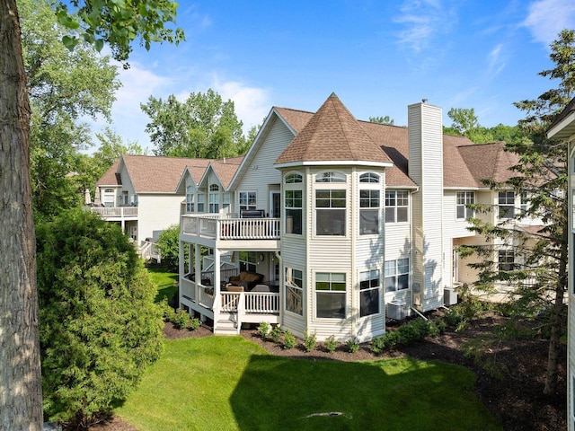 102 Abbey Ridge Ct Unit 102, Fontana, WI 53125 - back of property with a wooden deck, a chimney, a lawn, and roof with shingles