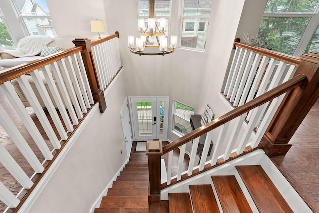 102 Abbey Ridge Ct Unit 102, Fontana, WI 53125 - staircase featuring a chandelier, wood finished floors, and a towering ceiling
