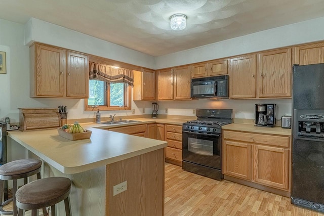 119 N 12th Ave, Monroe, WI 53566 - kitchen featuring black appliances, a kitchen breakfast bar, light countertops, and light wood finished floors