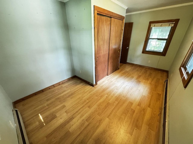 432 W Capitol Dr, Hartland, WI 53029 - unfurnished bedroom featuring a baseboard radiator, light wood-type flooring, a closet, baseboards, and crown molding