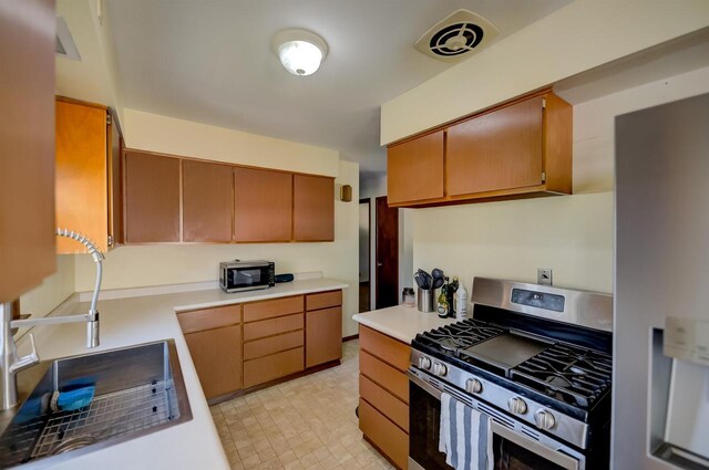 1516 Pierce Ave, Oshkosh, WI 54902 - kitchen with stainless steel appliances, a sink, light countertops, light flooring, and brown cabinets
