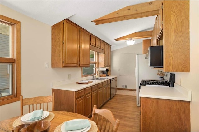 1711 Olive St, Stillwater, MN 55082 - kitchen featuring a sink, appliances with stainless steel finishes, lofted ceiling, brown cabinets, and light wood finished floors